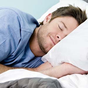 Man laying on pillow sleeping with a smile