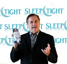 Dr. Michael Williams holding his SleepTight Mouthpiece with product logo in background 