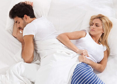 Wife pulling covers off husband