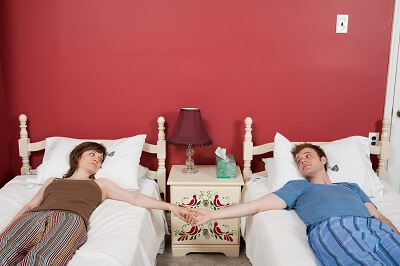 Couple sleeping in two twin size beds